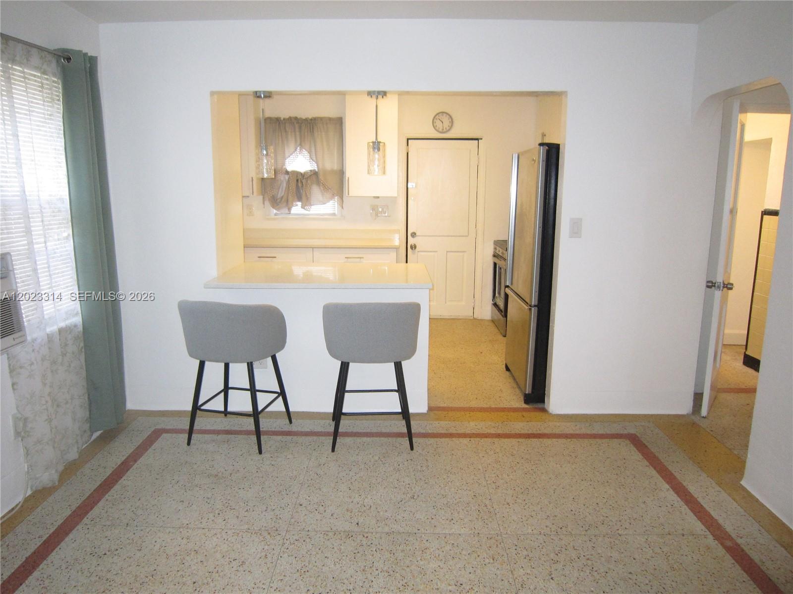A kitchen with a breakfast bar and two gray stools overlooks a dining area — 522 N 19th Ave # 5, Hollywood FL 33020, HOLLYWOOD, FL