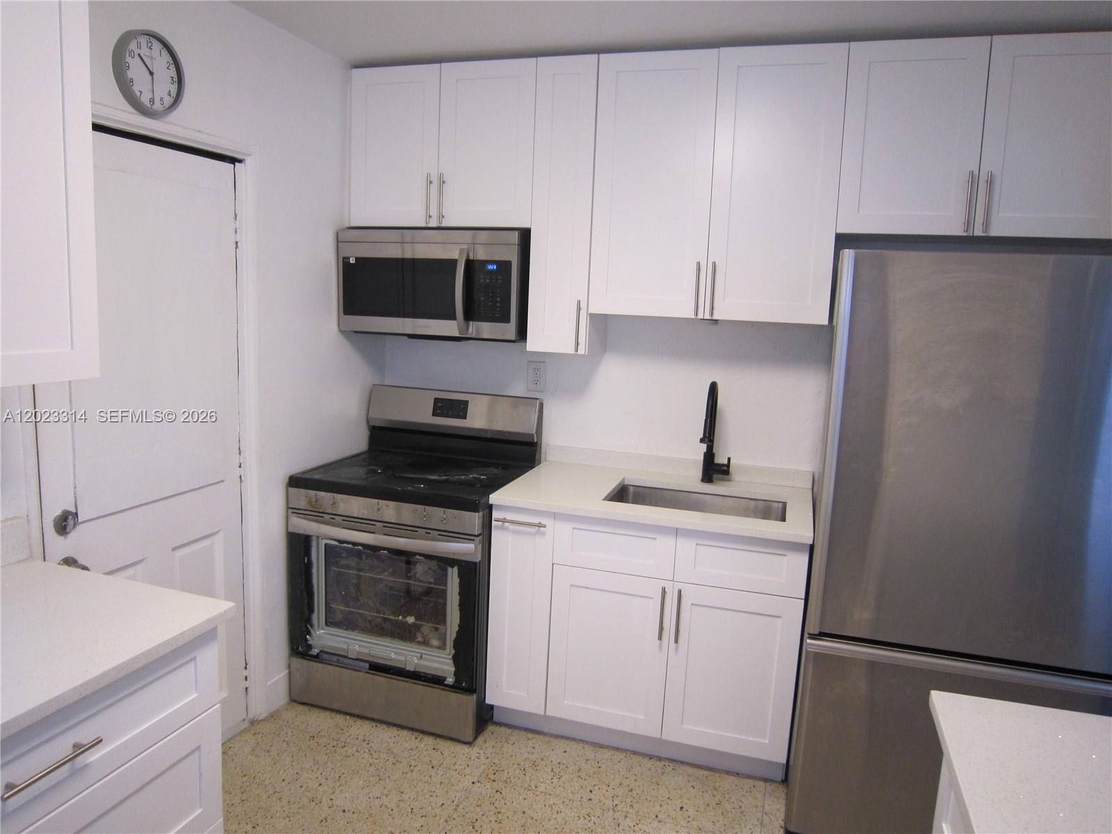 A small kitchen features white cabinets, stainless steel appliances, and a light-colored countertop — 522 N 19th Ave # 5, Hollywood FL 33020, HOLLYWOOD, FL