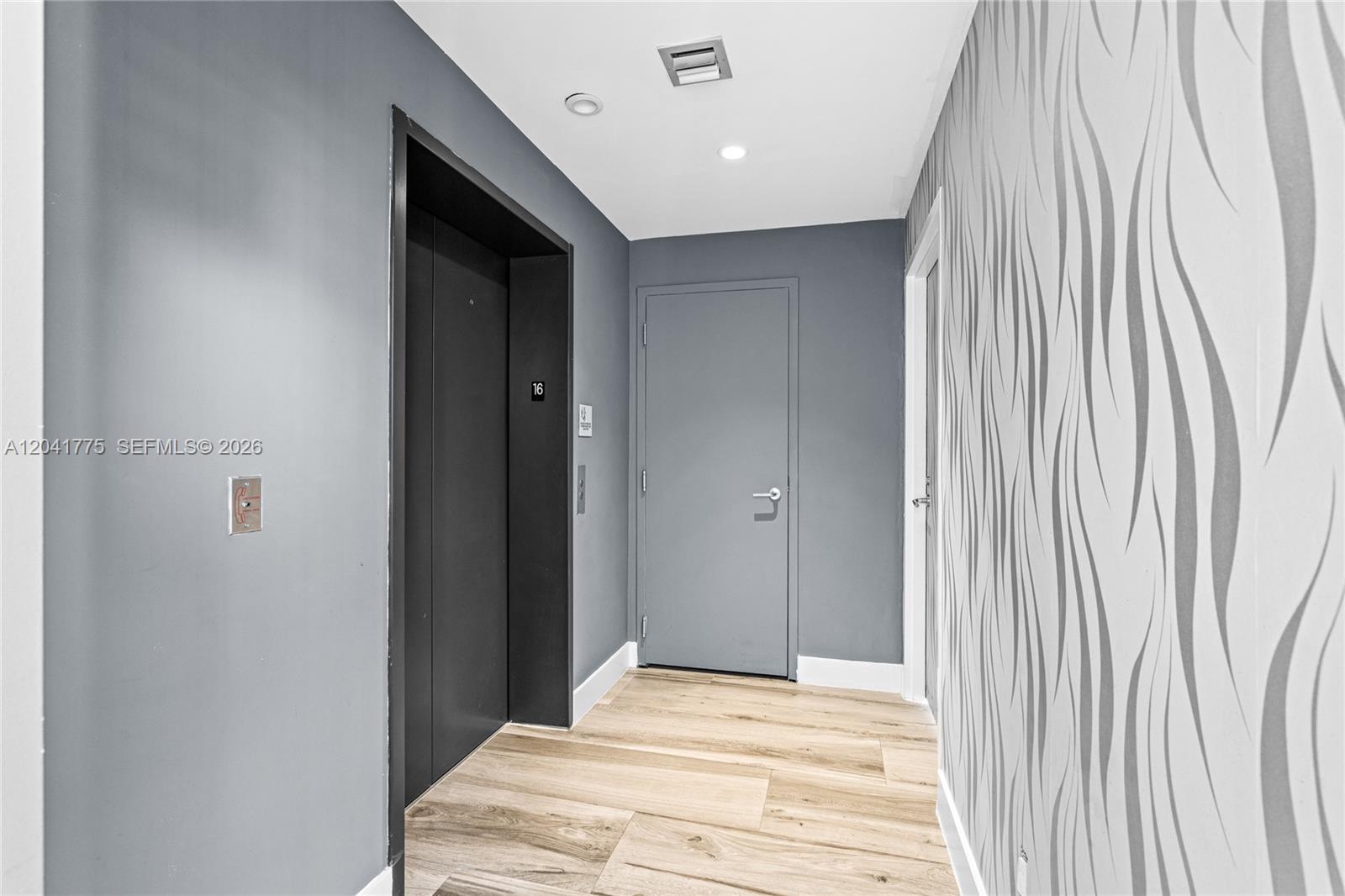 A hallway features a gray elevator, a matching door, and patterned wallpaper on one wall — 2900 NE 7th Ave # 1609, Miami FL 33137, MIAMI, FL