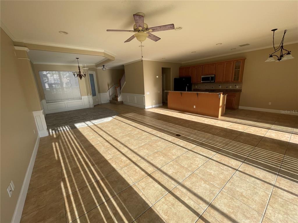 An open-concept kitchen and living area features tile flooring, wood cabinets, and a ceiling fan — 8314 VIA VERONA, ORLANDO, FL