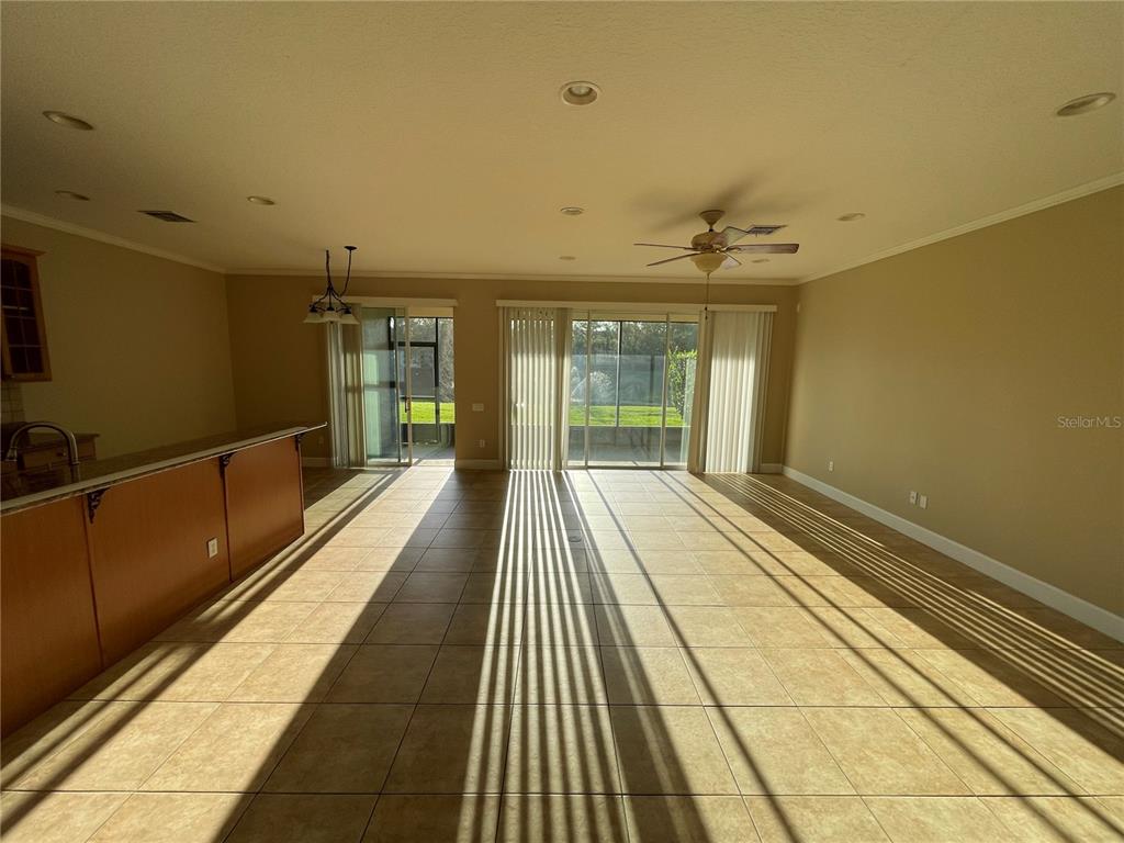 A spacious living area with tile flooring, a kitchen island, and sliding glass patio doors — 8314 VIA VERONA, ORLANDO, FL