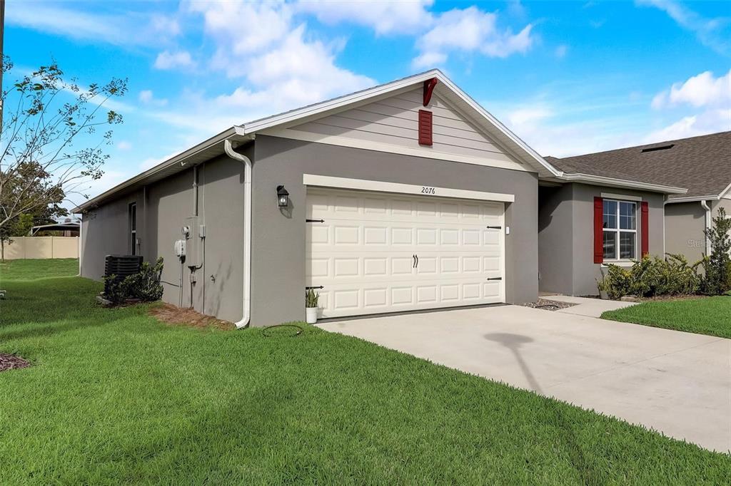 A gray single-story house with a white garage door, red shutters, and a green lawn — 2076 TAY WES DR, ST CLOUD, FL