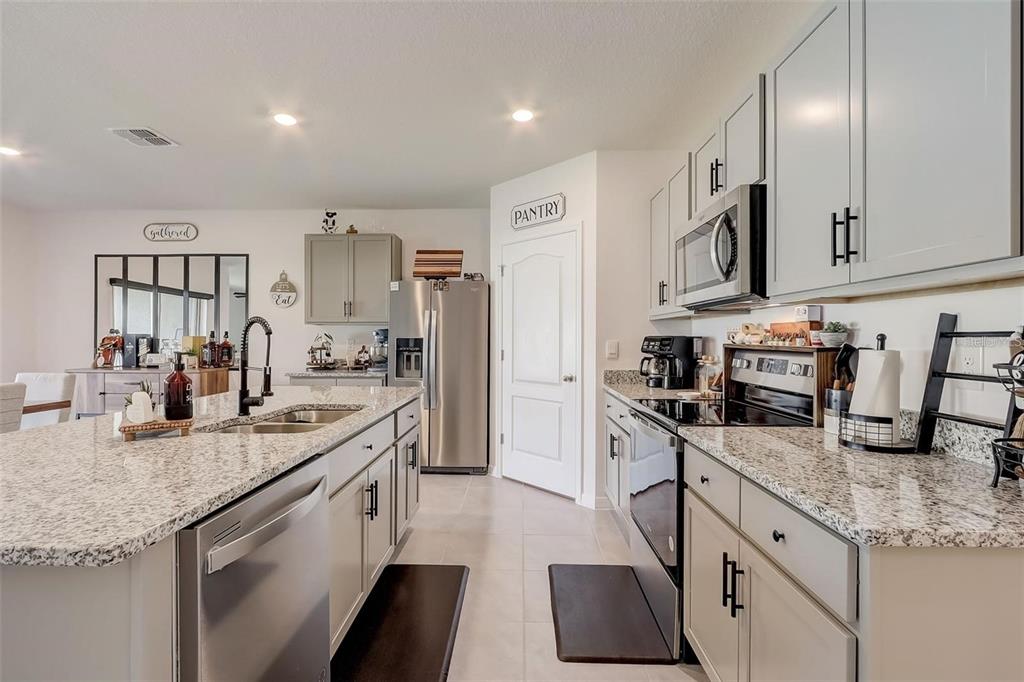 A kitchen features light gray cabinets, granite countertops, stainless steel appliances, and a central island — 2076 TAY WES DR, ST CLOUD, FL