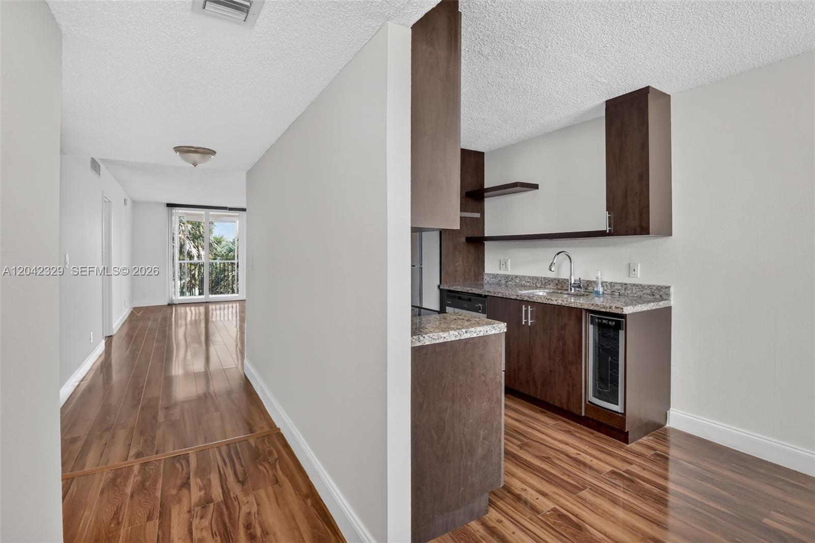 A kitchen with dark wood cabinets and granite countertops opens into a living area — 250 Jacaranda Dr # 411, Plantation FL 33324, PLANTATION, FL