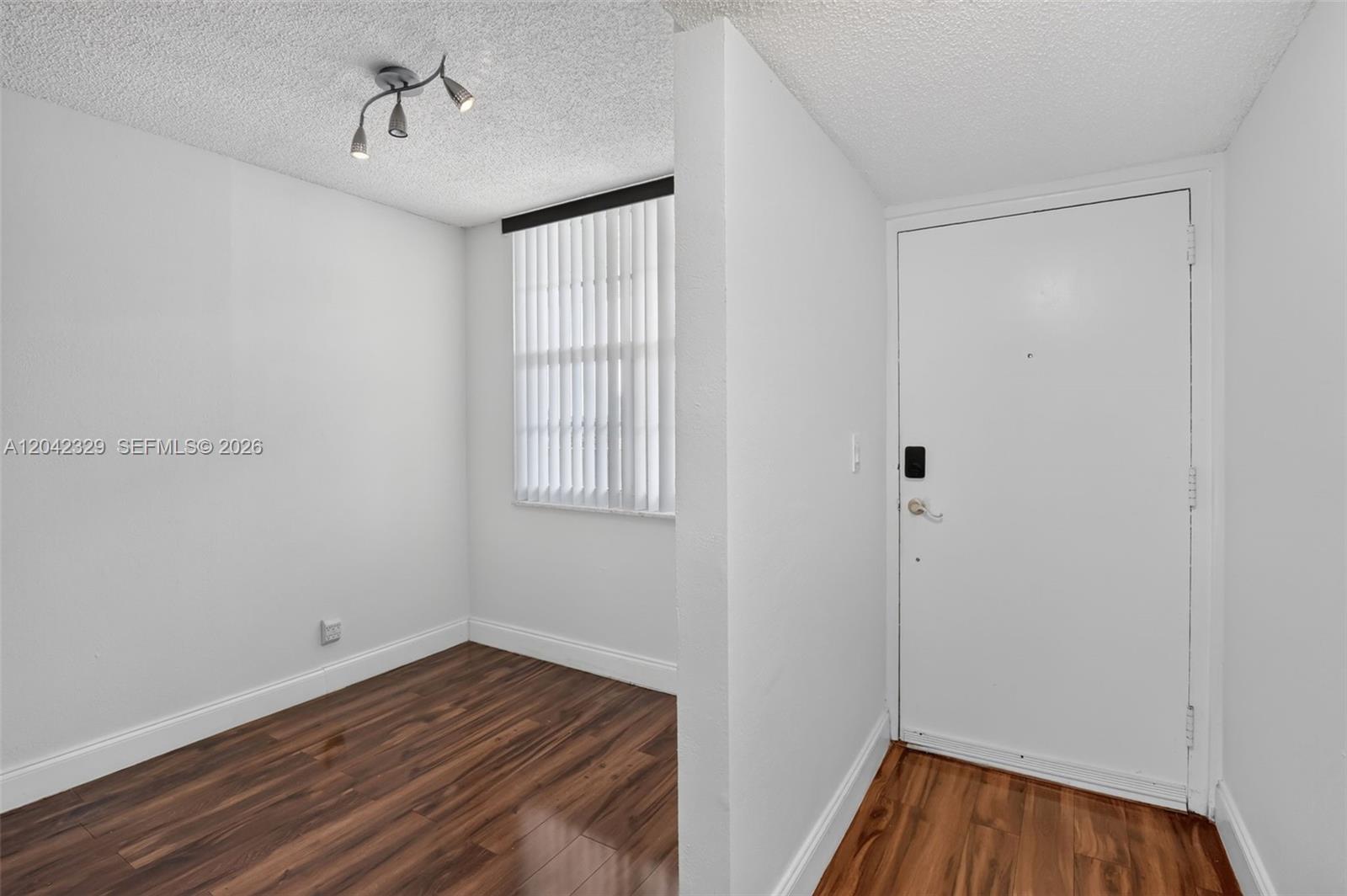 An entryway leads into a small room with white walls, wood flooring, and vertical blinds — 250 Jacaranda Dr # 411, Plantation FL 33324, PLANTATION, FL