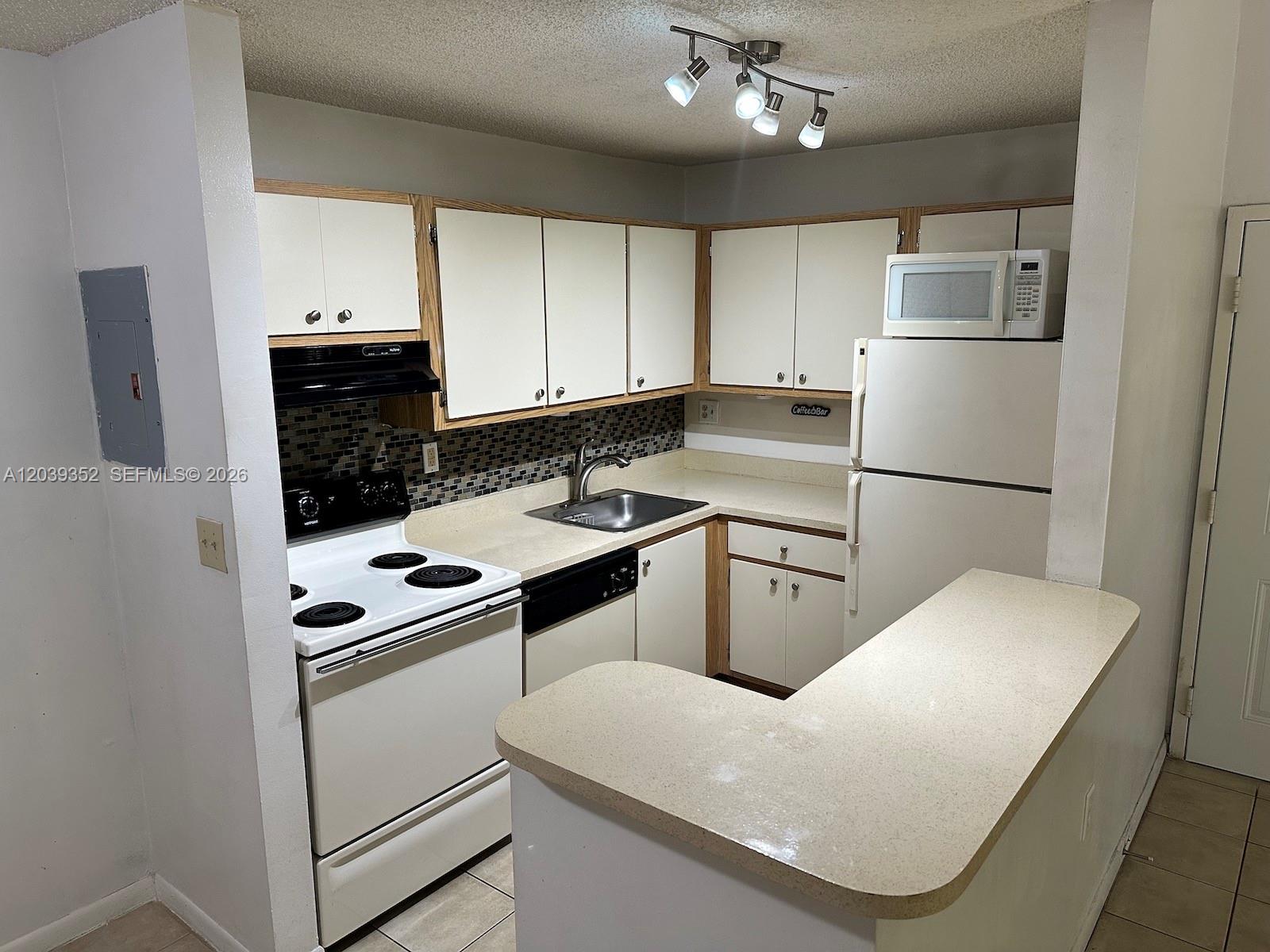 A kitchen features white cabinets, a white stove, a refrigerator, and a beige countertop — 7200 NW 179th St # 311, Hialeah FL 33015, HIALEAH, FL