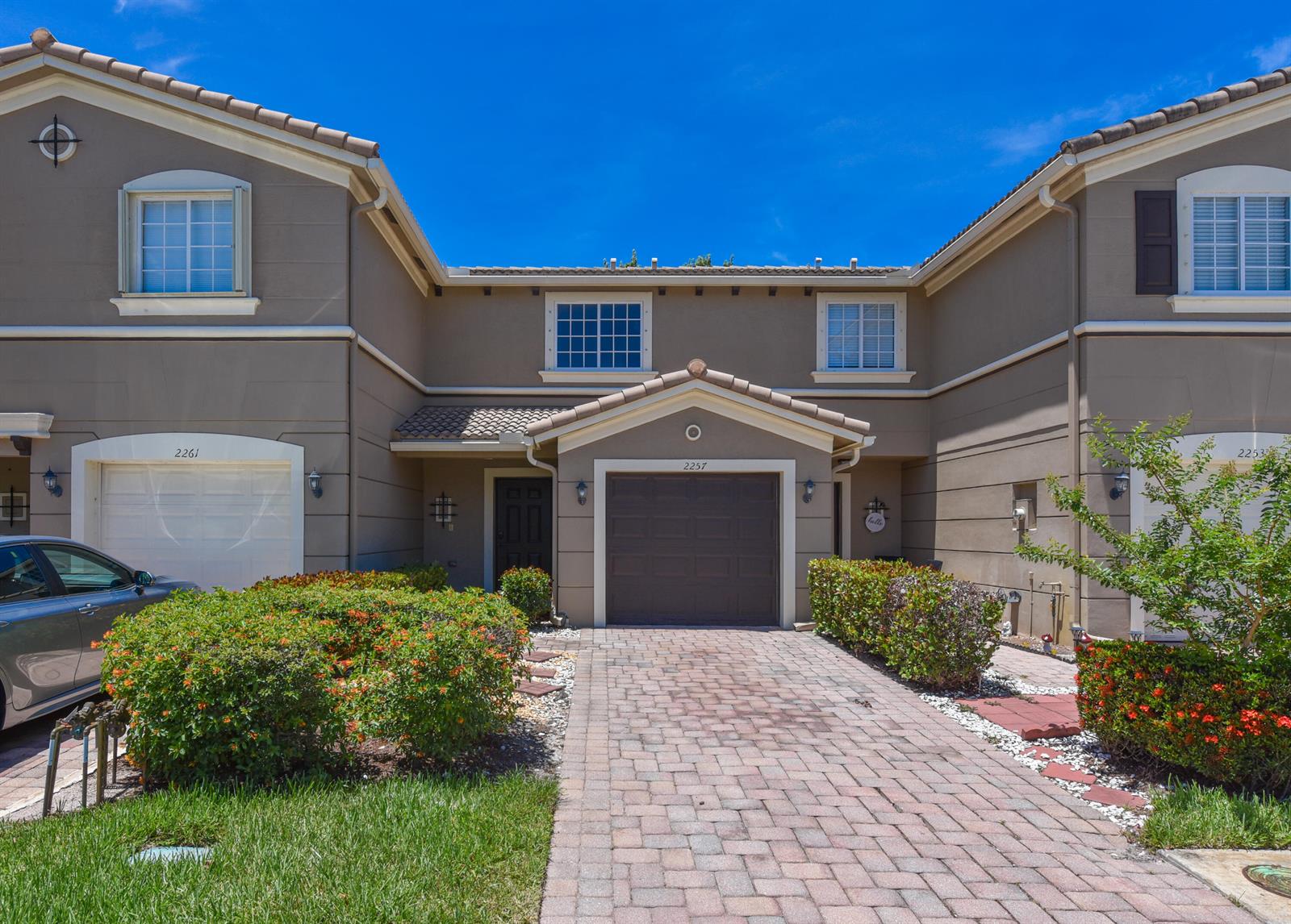 A two-story townhouse exterior features a brick paver driveway, a garage, and landscaped bushes — 2257 SW Marshfield Court, FL 34953, FL