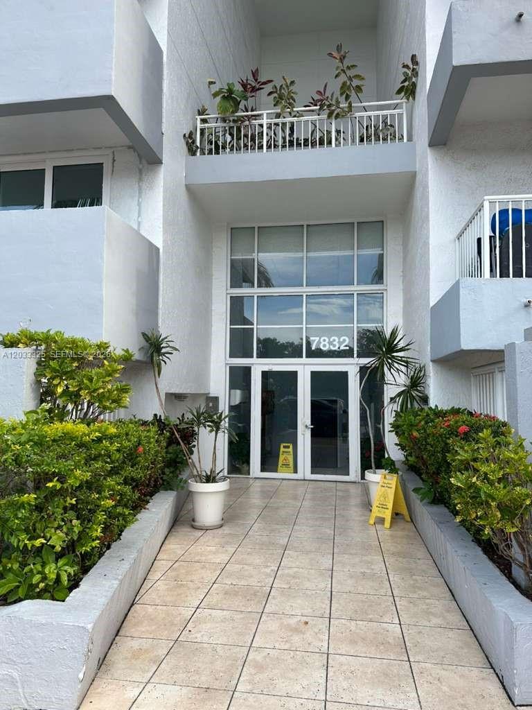 A multi-story white apartment building stands behind palm trees and street signs — 7832 Collins Ave # 406, Miami Beach FL 33141, MIAMI BEACH, FL