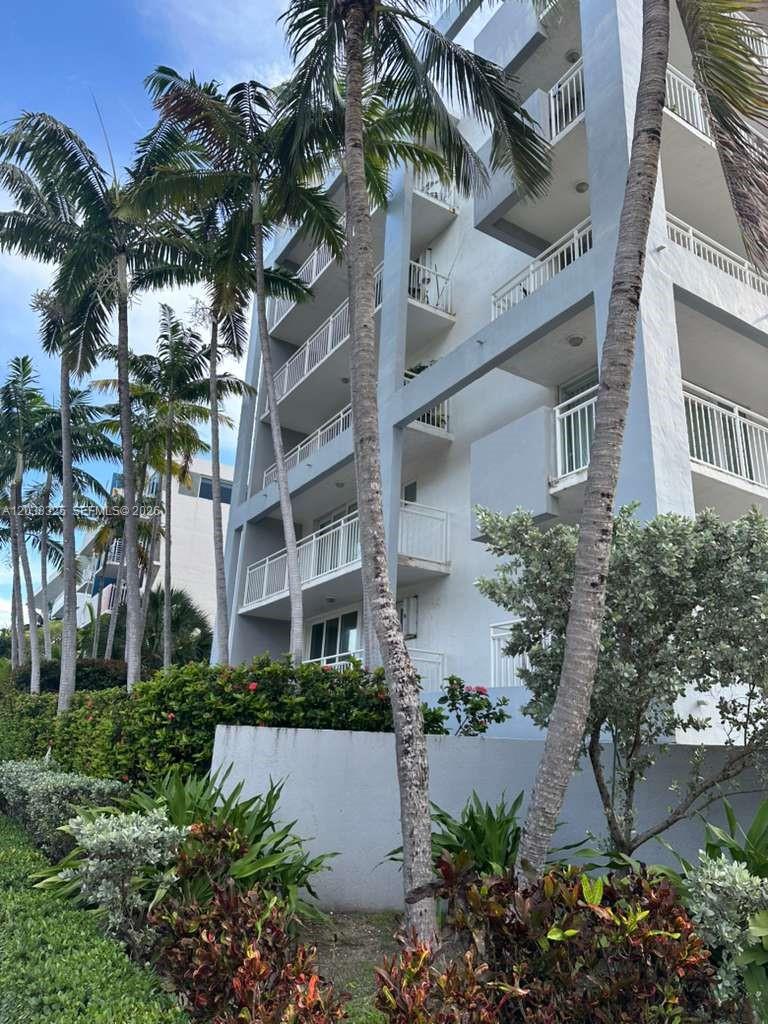 A multi-story apartment building with balconies stands behind palm trees and landscaping — 7832 Collins Ave # 406, Miami Beach FL 33141, MIAMI BEACH, FL