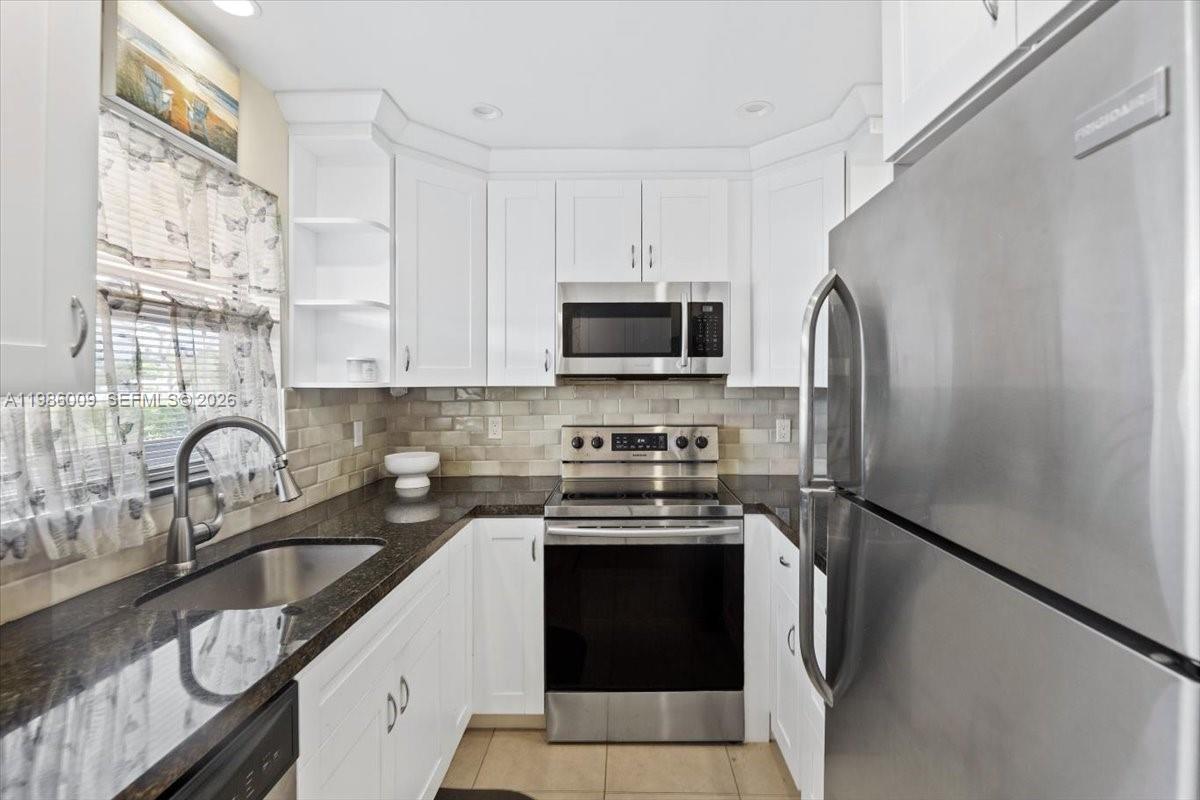 A compact kitchen features white cabinets, stainless steel appliances, and dark granite countertops — 2755 W Atlantic Ave # 2208, Delray Beach FL 33445, DELRAY BEACH, FL