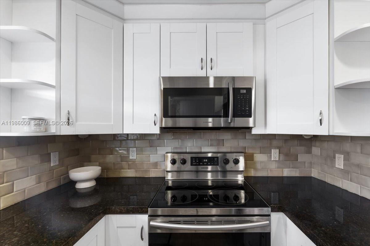 A kitchen features white cabinets, a stainless steel microwave, a glass-top stove, and subway tile — 2755 W Atlantic Ave # 2208, Delray Beach FL 33445, DELRAY BEACH, FL