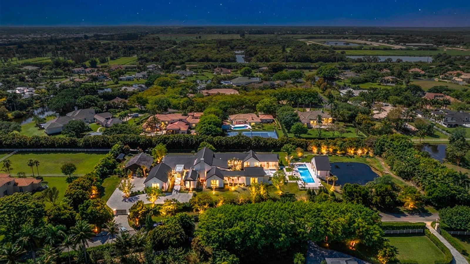 An aerial night view of a large modern estate featuring a pool and landscaped grounds — 10468 El Caballo Court, Delray Beach FL 33446, DELRAY BEACH, FL