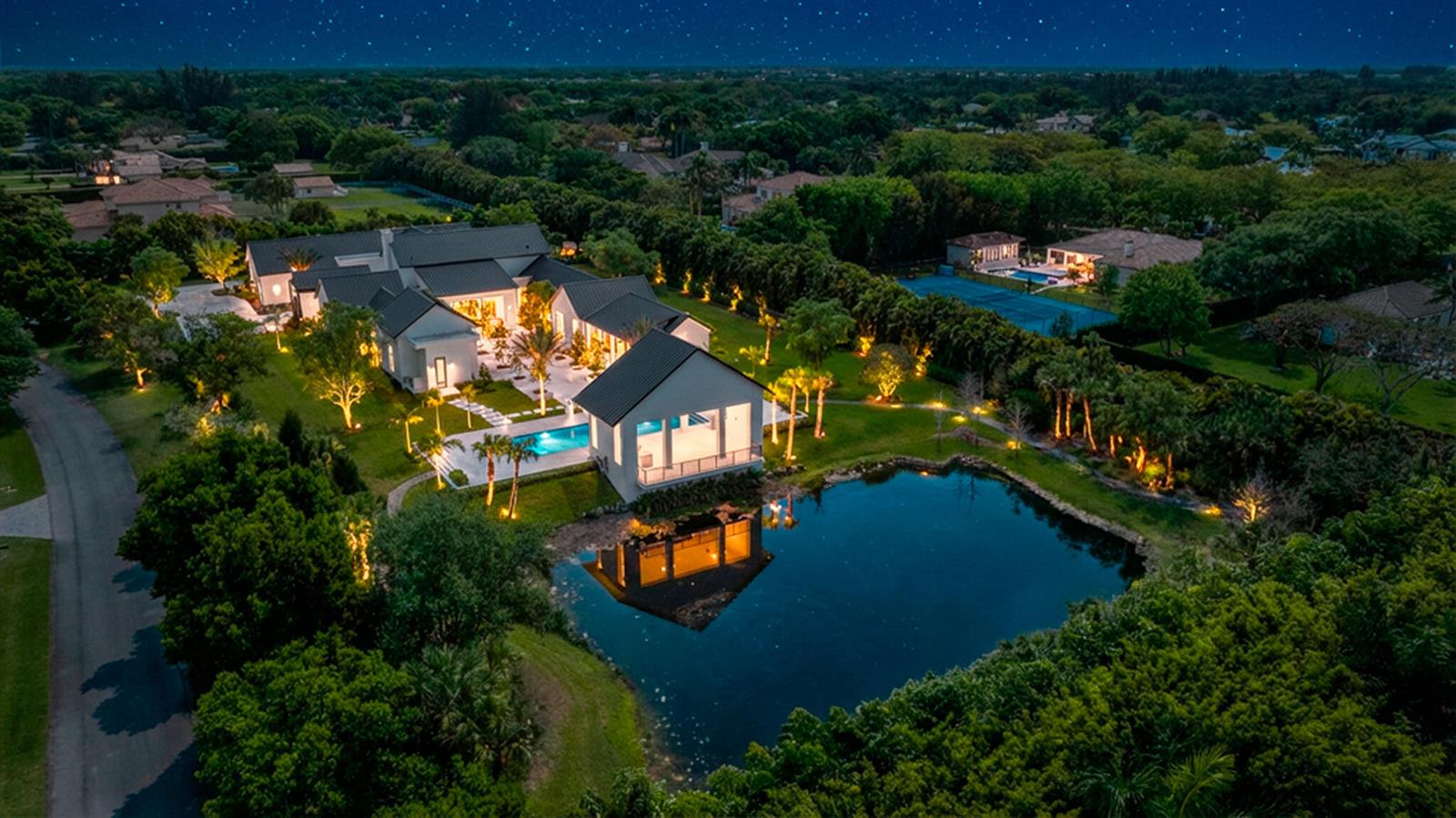 An aerial night view of a modern house with a pool and pond — 10468 El Caballo Court, Delray Beach FL 33446, DELRAY BEACH, FL