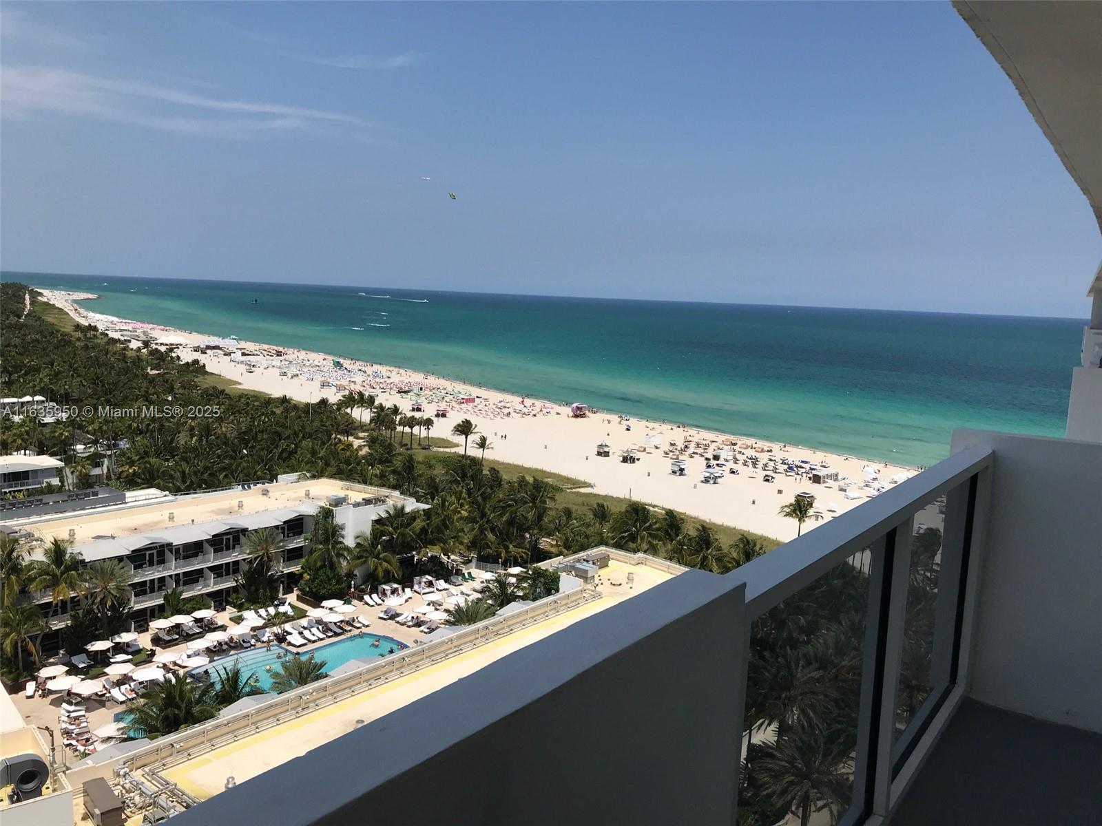 A high-angle view from a balcony overlooks a beach, ocean, and a swimming pool area — 100 Lincoln Rd # 1633, Miami Beach FL 33139, MIAMI BEACH, FL