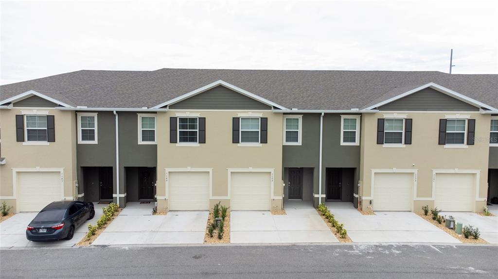 An exterior view of a multi-unit townhouse complex with attached garages and paved driveways — 1153 BLUE JAY DRIVE, DAVENPORT, FL