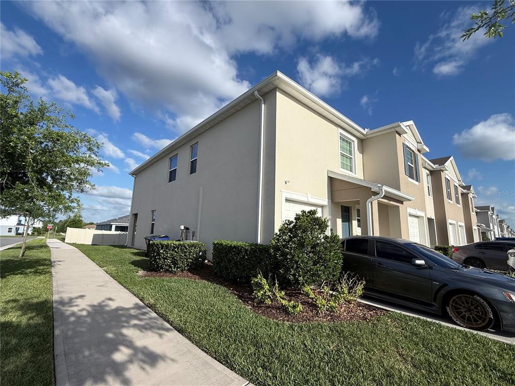 A two-story townhouse exterior with a beige stucco facade, a driveway, and a sidewalk — 2354 TAY WES DRIVE, ST CLOUD, FL