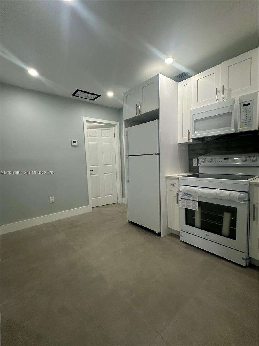 A kitchen features white cabinetry, white appliances, and light gray tile flooring — 1628 NW 15th St # B, Miami FL 33125, MIAMI, FL