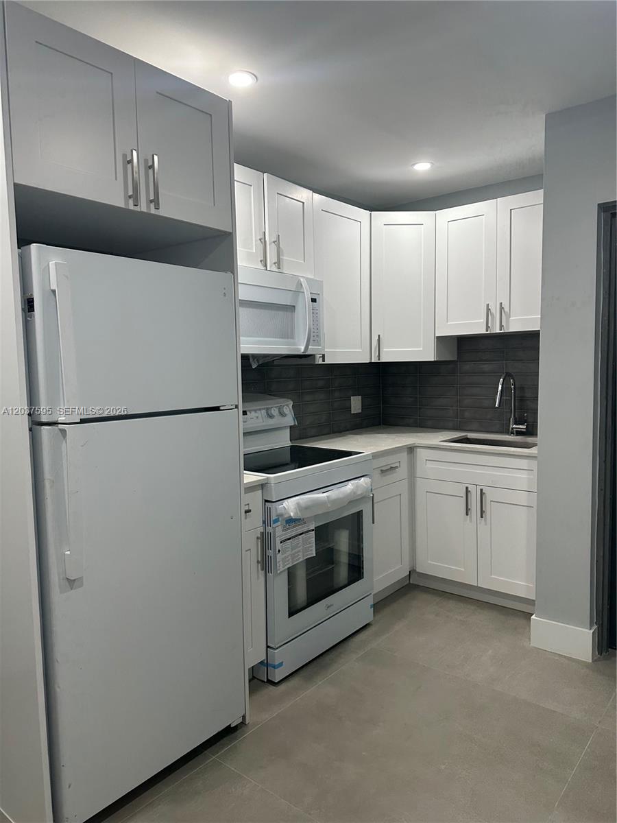 A kitchen features white shaker cabinets, stainless steel appliances, and a dark gray tiled backsplash — 1628 NW 15th St # B, Miami FL 33125, MIAMI, FL
