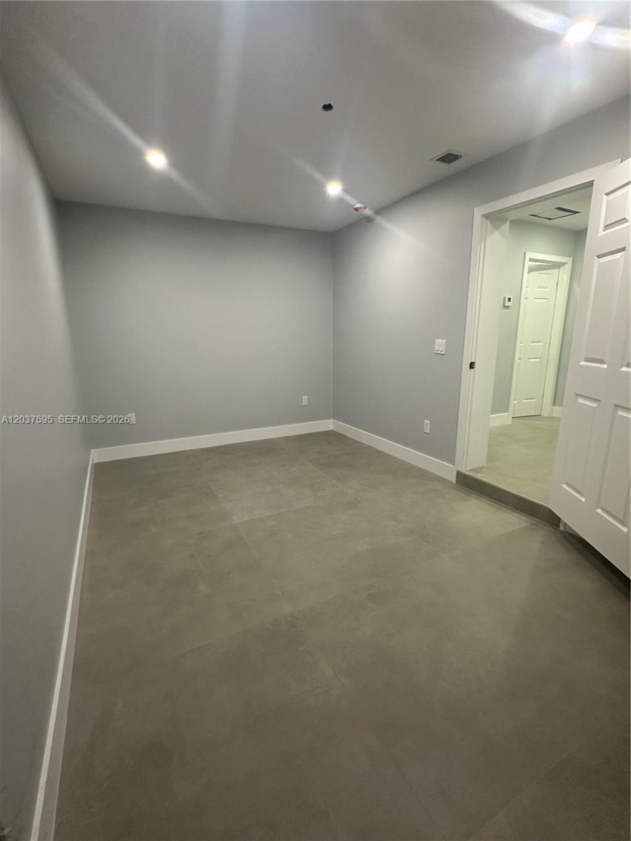 An empty room features gray walls, white baseboards, and large gray floor tiles — 1628 NW 15th St # B, Miami FL 33125, MIAMI, FL