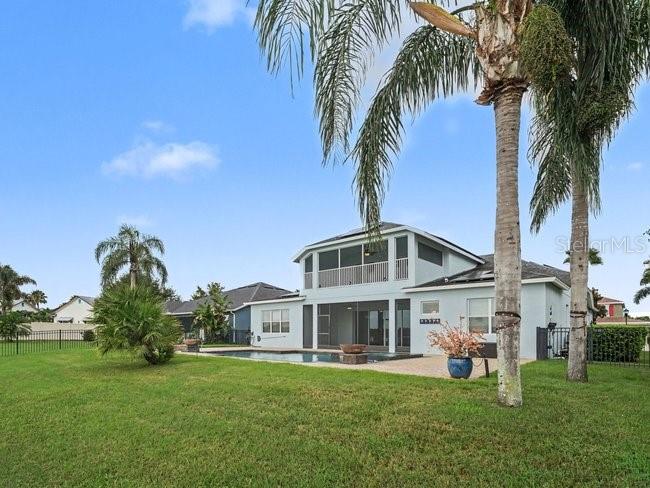 A two-story house with a screened-in pool and patio sits on a grassy lawn — 11323 LAKE LUCAYA DRIVE, RIVERVIEW, FL