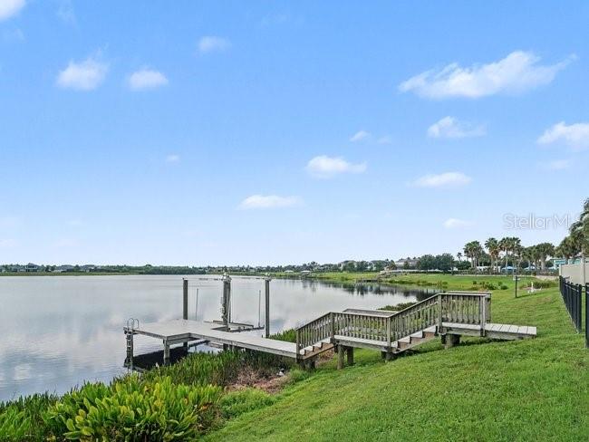 A wooden dock with stairs extends from a grassy bank into a calm lake — 11323 LAKE LUCAYA DRIVE, RIVERVIEW, FL