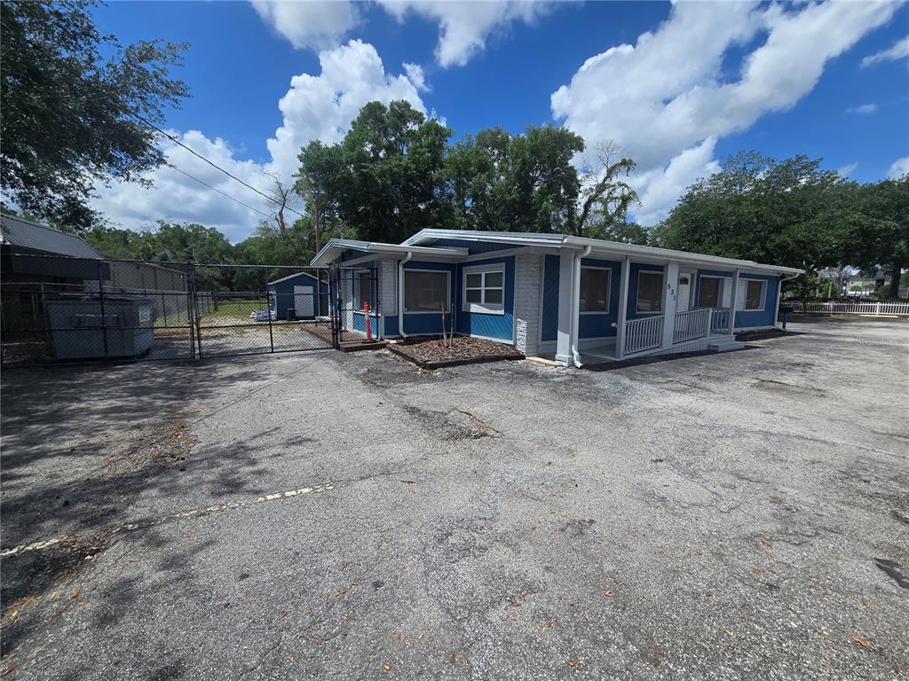 A blue and white single-story commercial building with a paved parking lot and chain-link fence — 531 DOG TRACK ROAD, LONGWOOD, FL