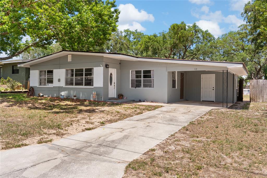 A single-story house with a gray exterior, a concrete driveway, and an attached carport — 12 BEVERLY DRIVE, FROSTPROOF, FL