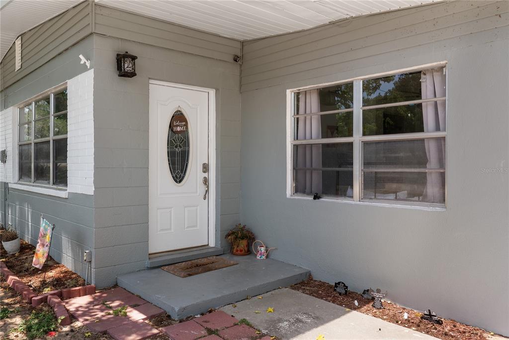 The exterior of a gray house features a white front door and two windows — 12 BEVERLY DRIVE, FROSTPROOF, FL
