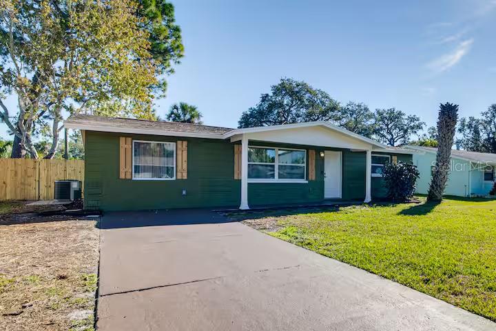 A green single-story house with a white front door and a concrete driveway — 7252 DIANNE DRIVE, NEW PORT RICHEY, FL