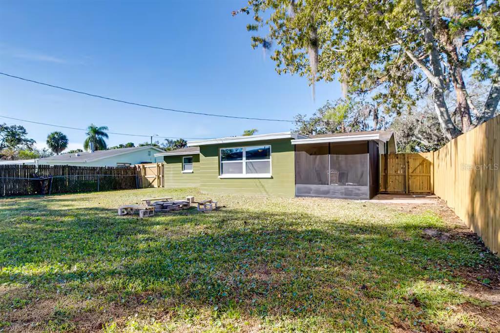 The backyard features a green house with a screened-in porch and a wooden fence — 7252 DIANNE DRIVE, NEW PORT RICHEY, FL
