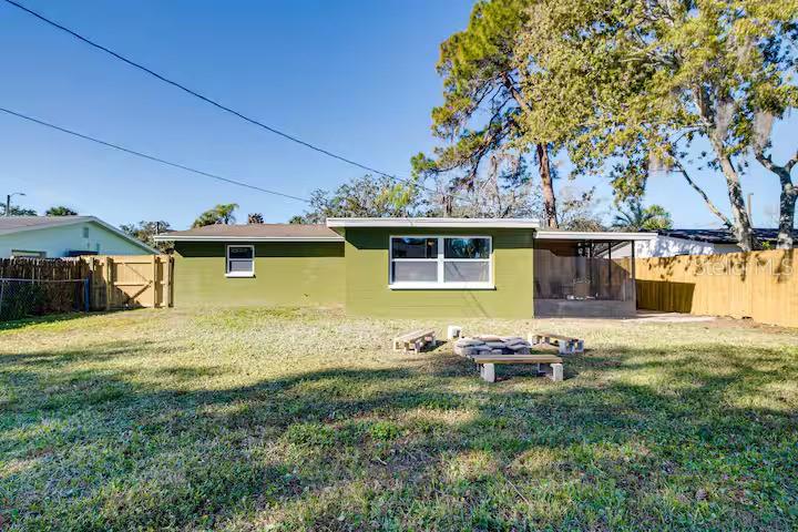 The exterior of a green, single-story house with a backyard fire pit and wooden benches — 7252 DIANNE DRIVE, NEW PORT RICHEY, FL