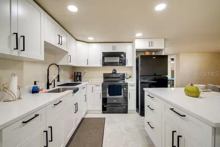 A kitchen with white cabinets, black appliances, and a central island with white countertops — 7252 DIANNE DRIVE, NEW PORT RICHEY, FL