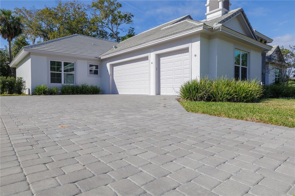 A single-story house with a paved driveway, two garage doors, and a tiled roof — 110 NEW LEATHERWOOD DRIVE, PALM COAST, FL
