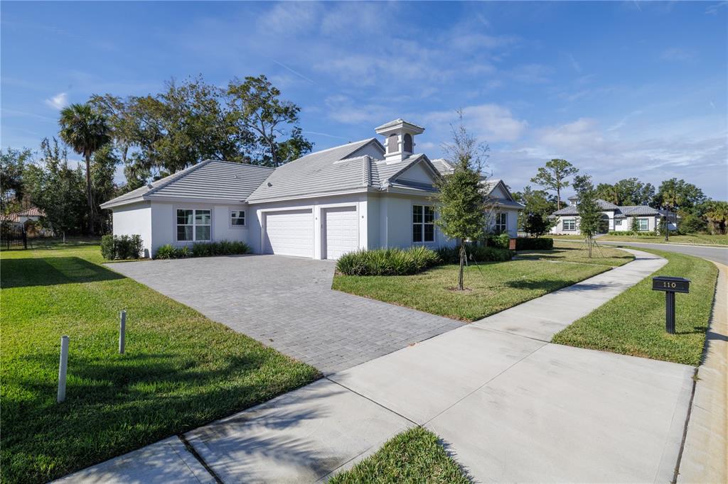 A single-story house with a white exterior, a tiled roof, and a paved driveway — 110 NEW LEATHERWOOD DRIVE, PALM COAST, FL