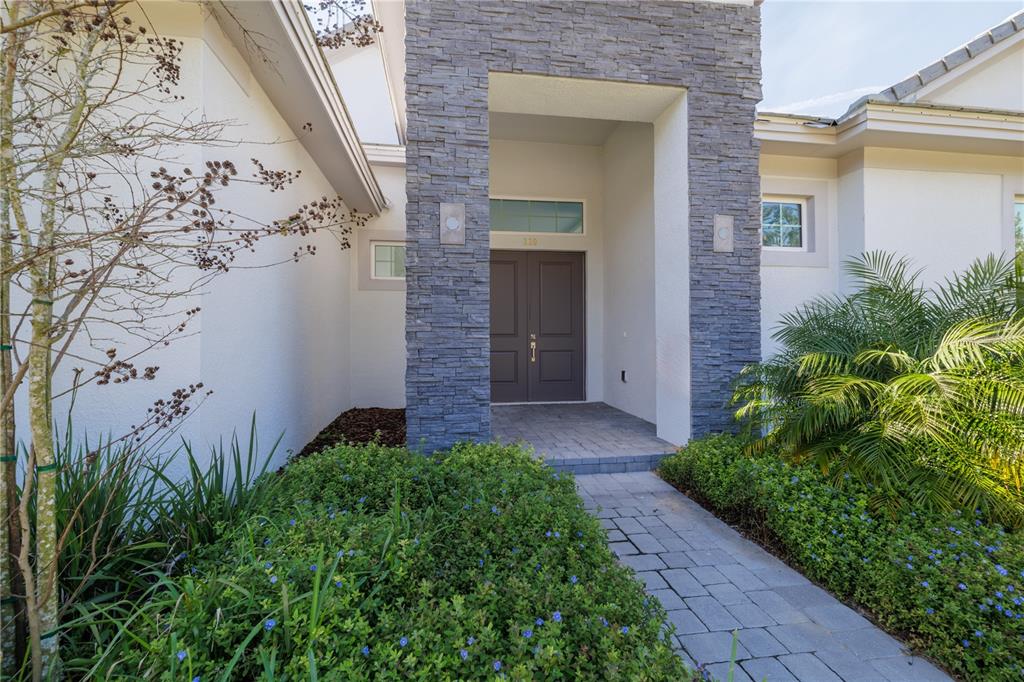 The front entrance features a stone-clad entryway, double doors, and a paved walkway — 110 NEW LEATHERWOOD DRIVE, PALM COAST, FL