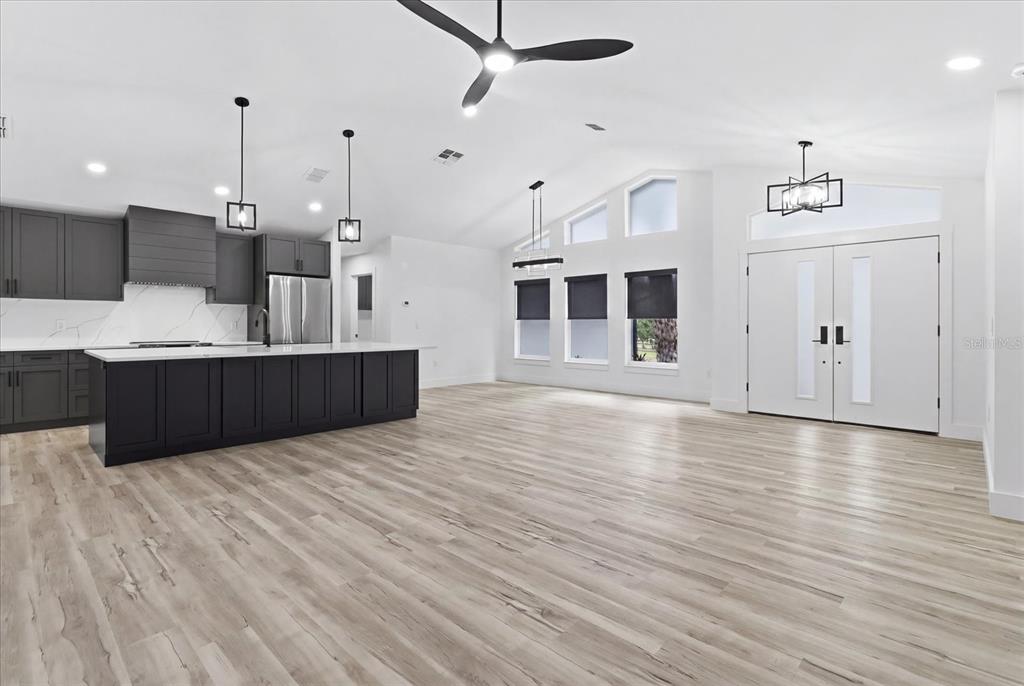 A modern open-concept kitchen and living area features dark cabinetry, a large island, and light flooring — 2995 N BRAVO DRIVE, BEVERLY HILLS, FL