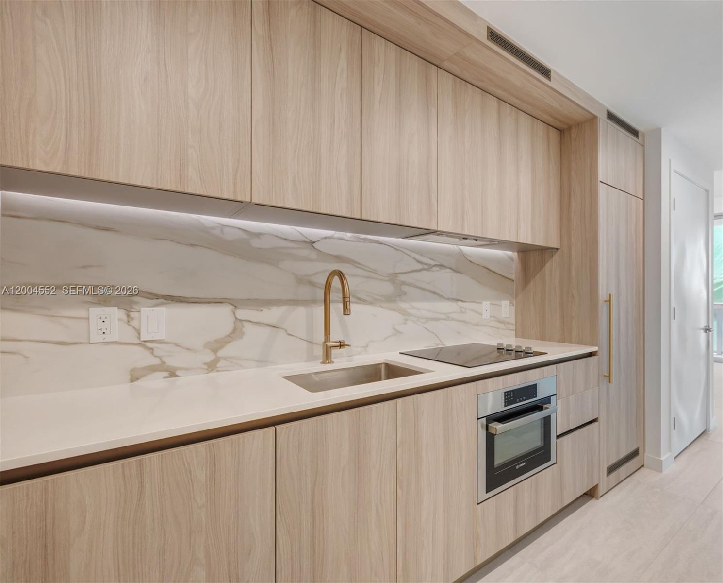 A modern kitchen features light wood cabinetry, a marble backsplash, and a stainless steel sink — 77 SE 5th St # 3205, Miami FL 33131, MIAMI, FL
