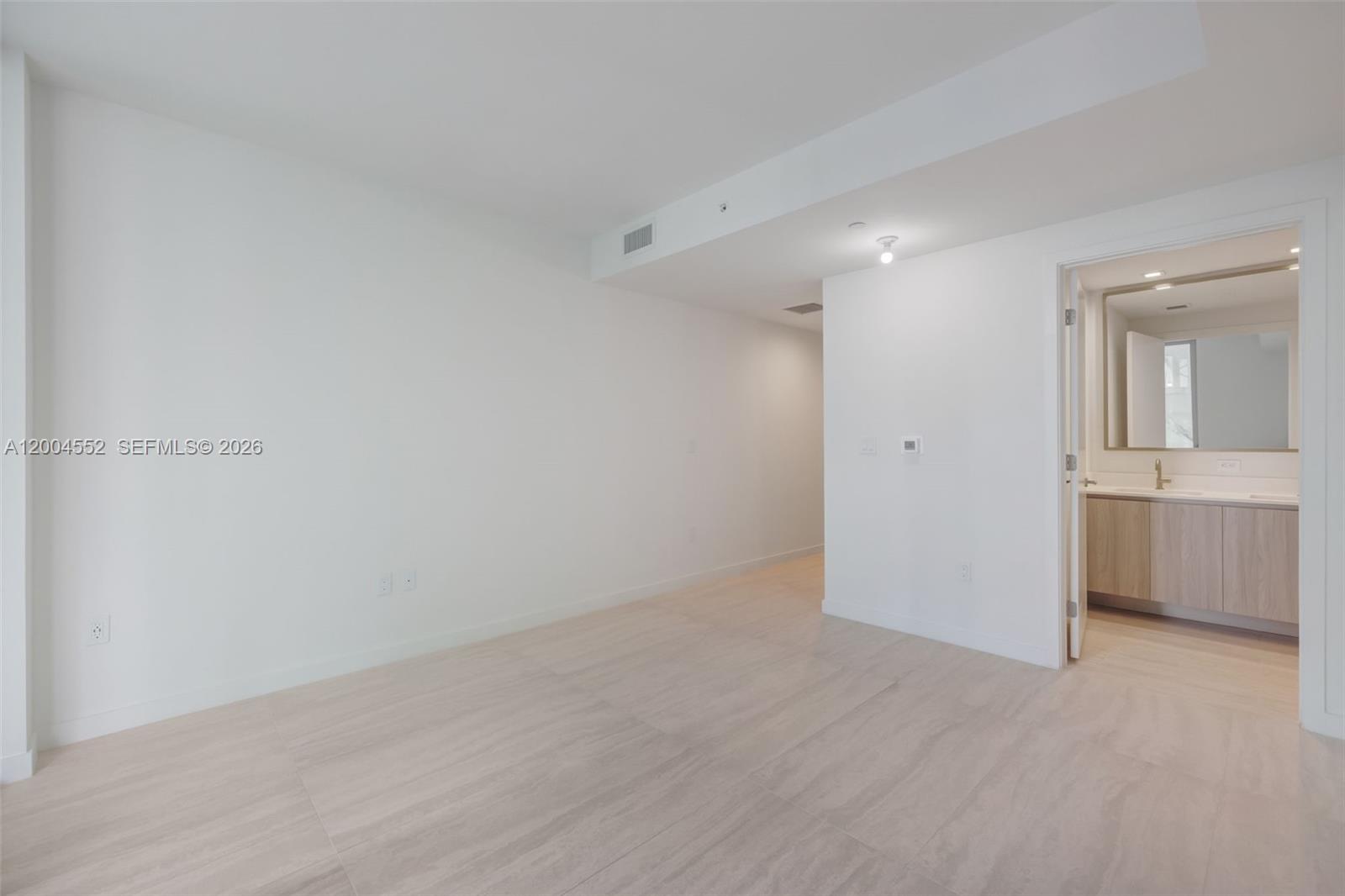A bright, empty room with light-colored tile flooring leads into an adjacent bathroom — 77 SE 5th St # 3205, Miami FL 33131, MIAMI, FL
