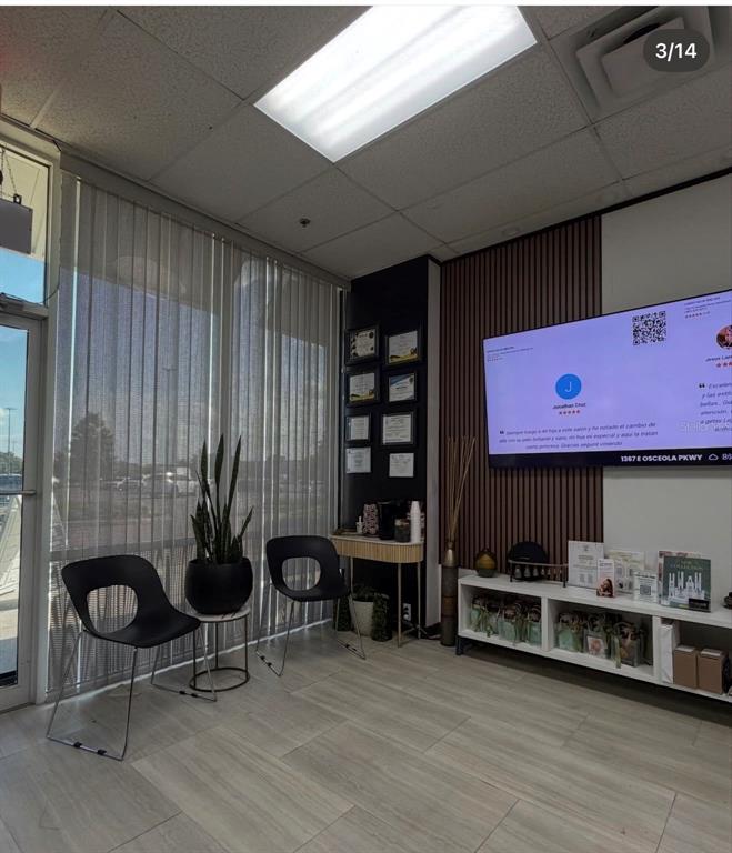 A waiting room features two black chairs, a plant, a television, and a white console — 1307 E OSCEOLA PARKWAY, KISSIMMEE, FL