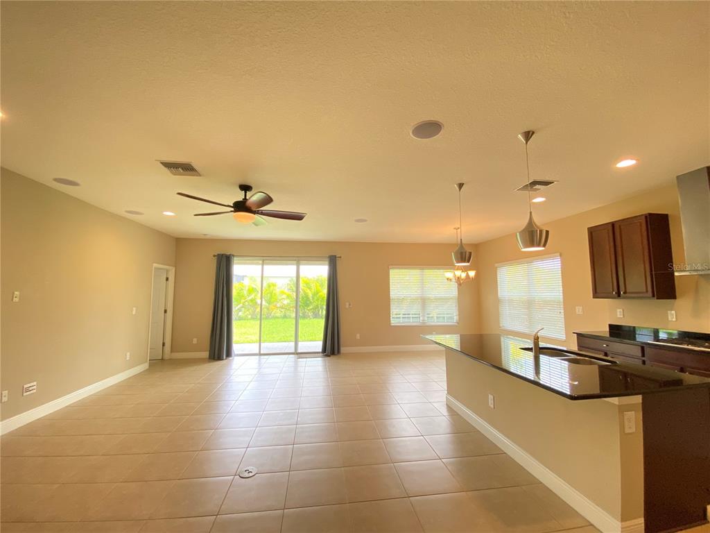 An open-concept kitchen and living area features tile flooring, dark cabinetry, and sliding glass doors — 6507 PARK TERRACE LANE, APOLLO BEACH, FL