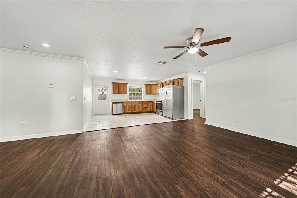 A spacious open-concept living area features wood-look flooring and an adjacent kitchen with wooden cabinets — 245 OAK RUN COURT, APOPKA, FL