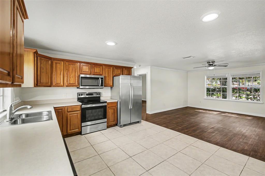 A kitchen with wood cabinets and stainless steel appliances opens into a living area — 245 OAK RUN COURT, APOPKA, FL