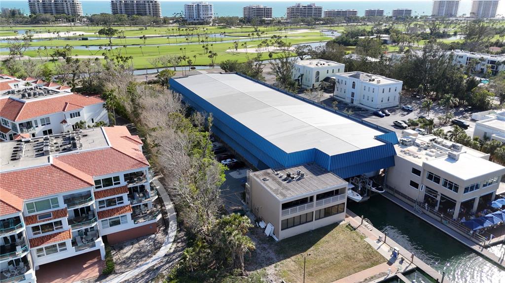 An aerial view shows a large boat storage facility next to residential buildings and water — 408 GULF OF MEXICO DRIVE UNIT 1214, LONGBOAT KEY, FL