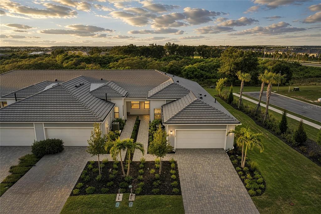An aerial view of a suburban duplex with tiled roofs, paver driveways, and landscaped front yards — 18808 INDIAN ROCK PLACE, LAKEWOOD RANCH, FL