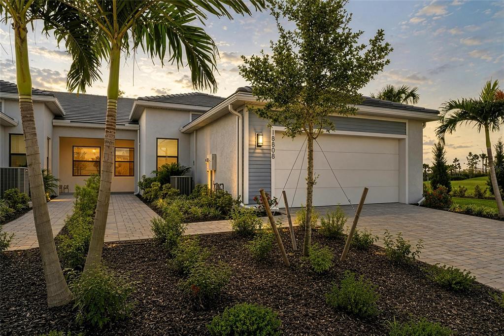 A single-story house exterior features a paved driveway, a two-car garage, and palm trees — 18808 INDIAN ROCK PLACE, LAKEWOOD RANCH, FL