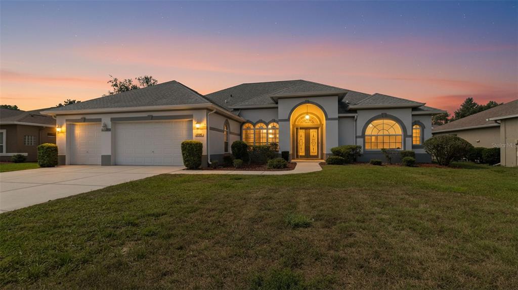 A single-story suburban house with a two-car garage and a covered arched entryway — 8722 MISSISSIPPI RUN, WEEKI WACHEE, FL