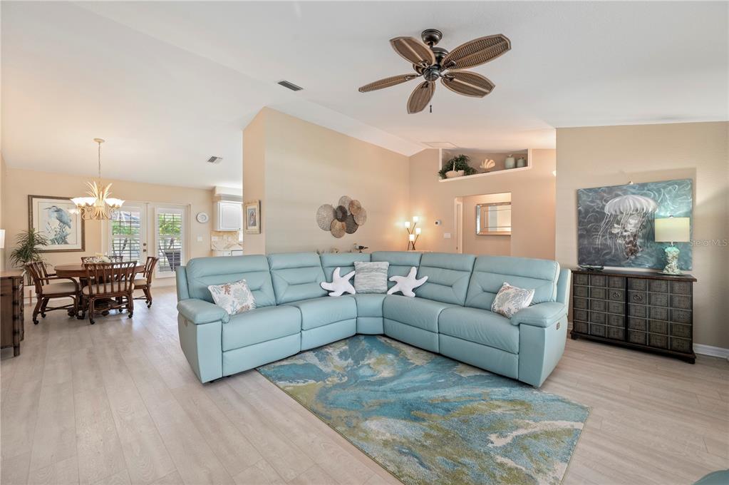 A living room features a light blue sectional sofa, a patterned area rug, and a ceiling fan — 23347 MULLINS AVENUE, PORT CHARLOTTE, FL
