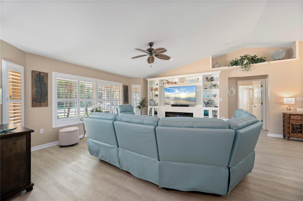 A living room features a light blue sectional sofa, built-in shelving, and light wood flooring — 23347 MULLINS AVENUE, PORT CHARLOTTE, FL
