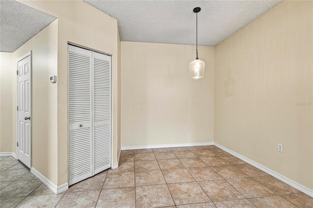 A dining area features beige walls, a pendant light, a closet, and tiled flooring — 5459 BENTGRASS DRIVE UNIT 2-110, SARASOTA, FL