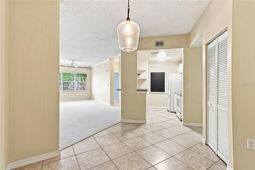 A tiled dining area leads into a carpeted living room and a kitchen with appliances — 5459 BENTGRASS DRIVE UNIT 2-110, SARASOTA, FL